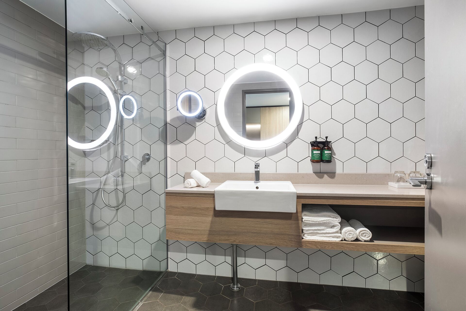 A modern bathroom with a glass shower enclosure, a vanity with a mirror, and a sink.