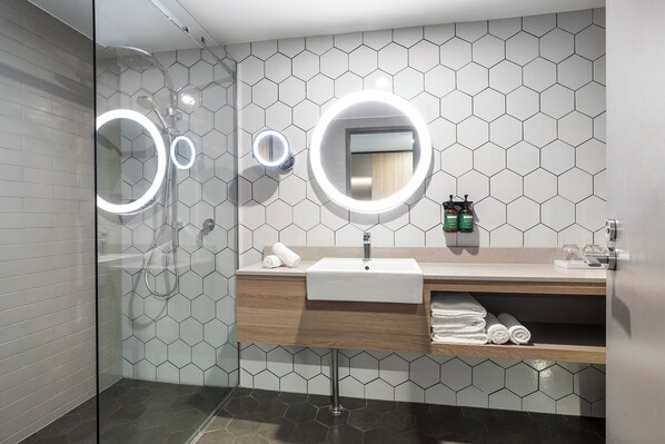 A modern bathroom with a glass shower enclosure, a vanity with a mirror, and a sink.