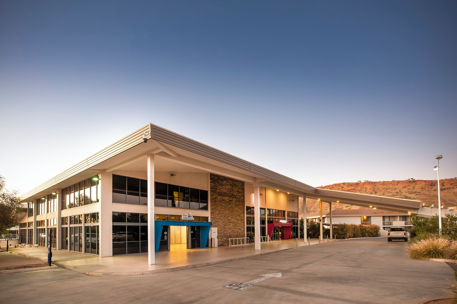A modern gas station with a covered fuel pump area, multiple service bays, and a clear sky.