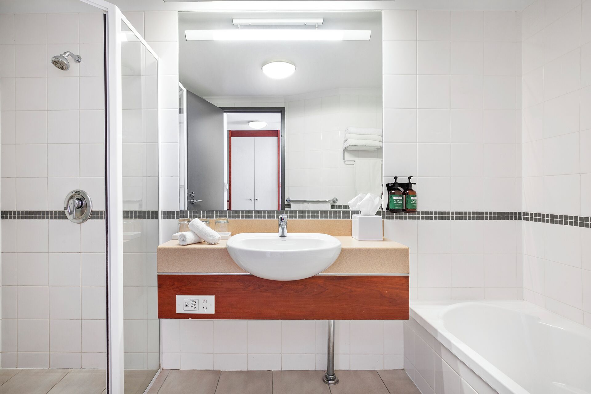 A modern bathroom with a white sink, mirror, and bathtub.
