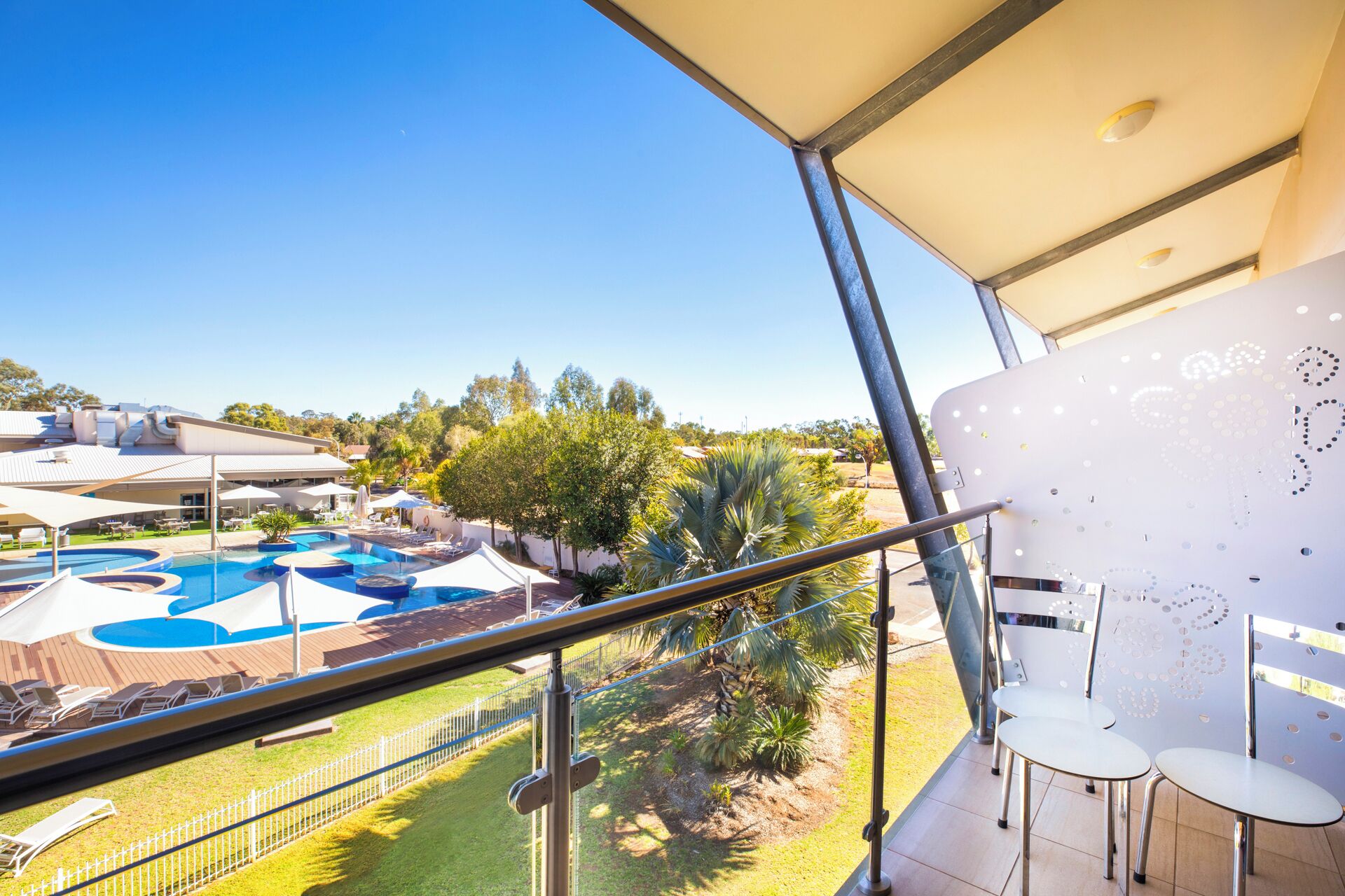 A pool area with multiple swimming pools, lounge chairs, and a view of the surrounding landscape.