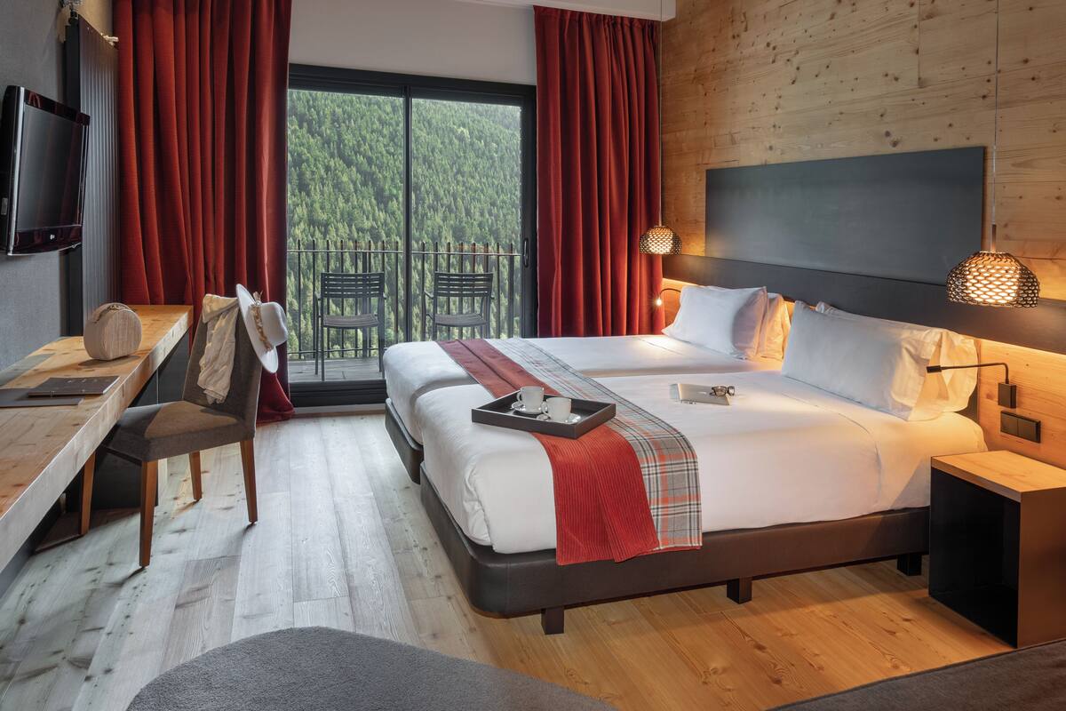 A modern hotel room with a large bed, a desk, and a TV.