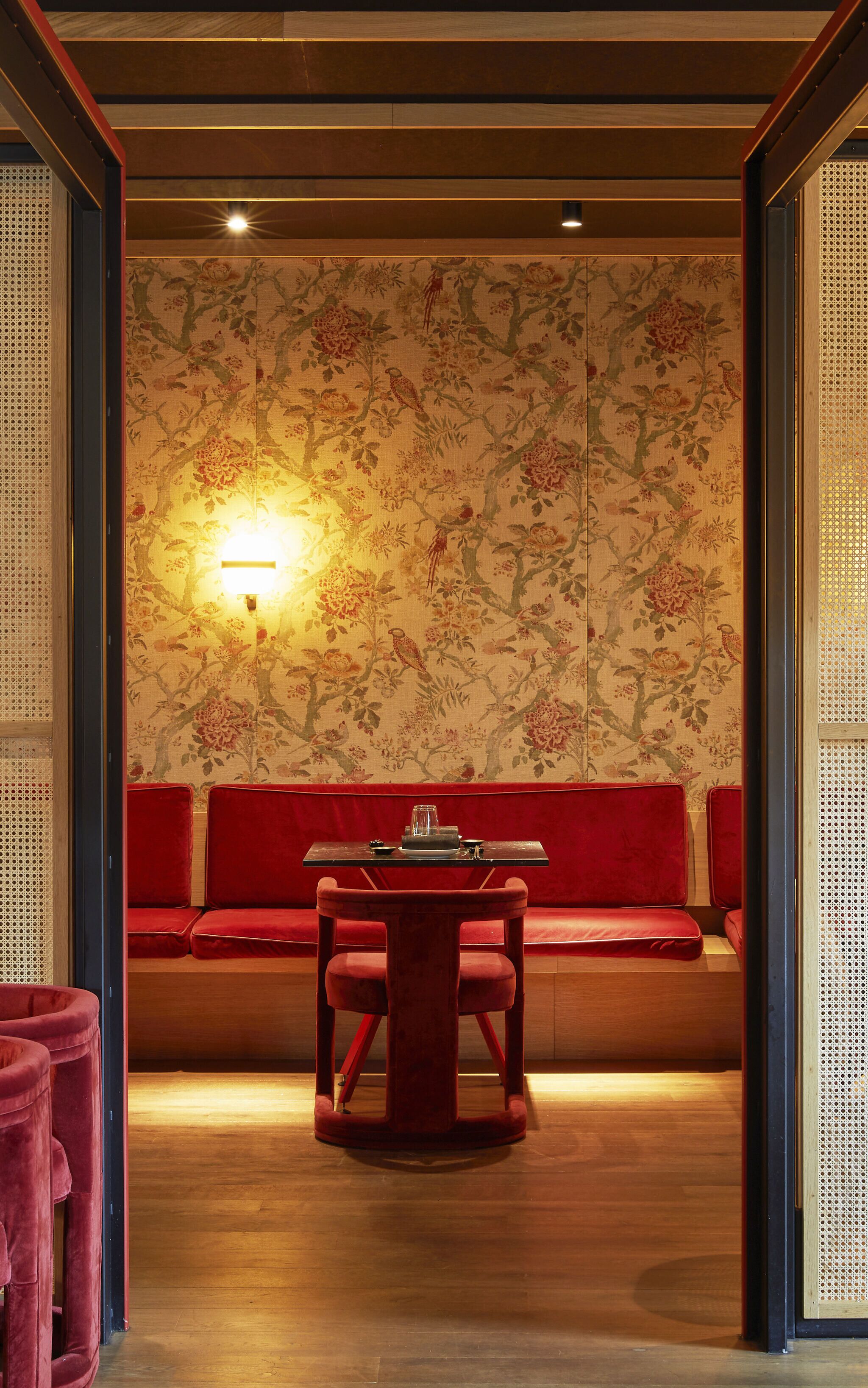 Una habitación tradicional con suelo de madera, un sofá rojo y una mesa con un centro de mesa de cristal.