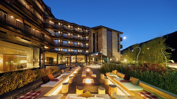 A hotel with outdoor seating areas, a fire pit, and a view of the mountains.