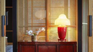 A wooden cabinet with a red lamp and a vase of white flowers.