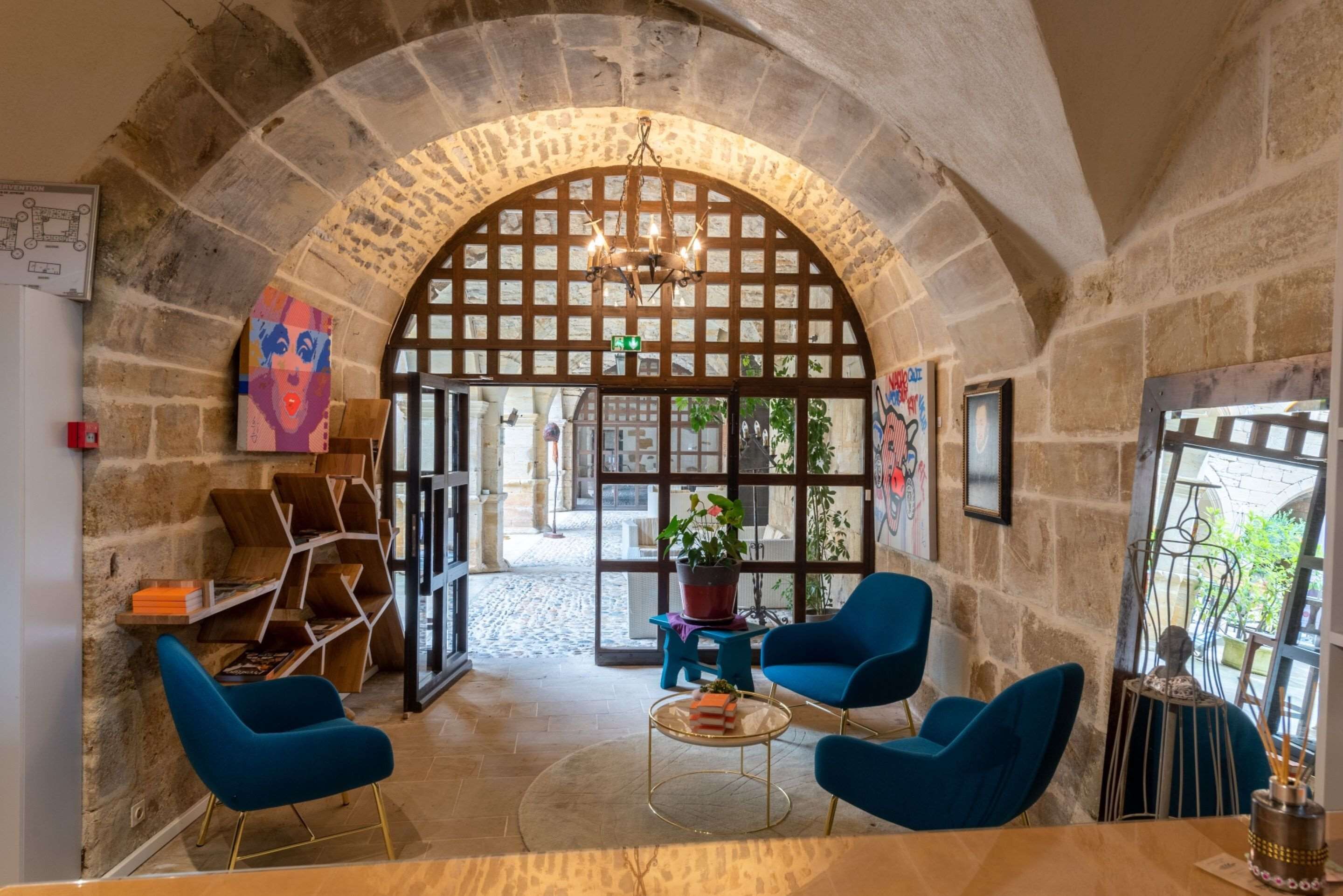 Un interior acogedor con un arco de piedra, sillas azules, una mesa redonda y una planta en maceta.