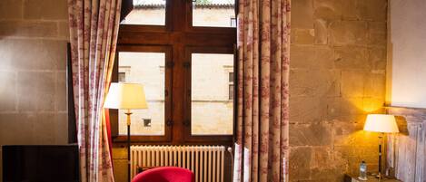 Una habitación de hotel con un sillón rojo, una cama con un sombrero de paja y dos lámparas.