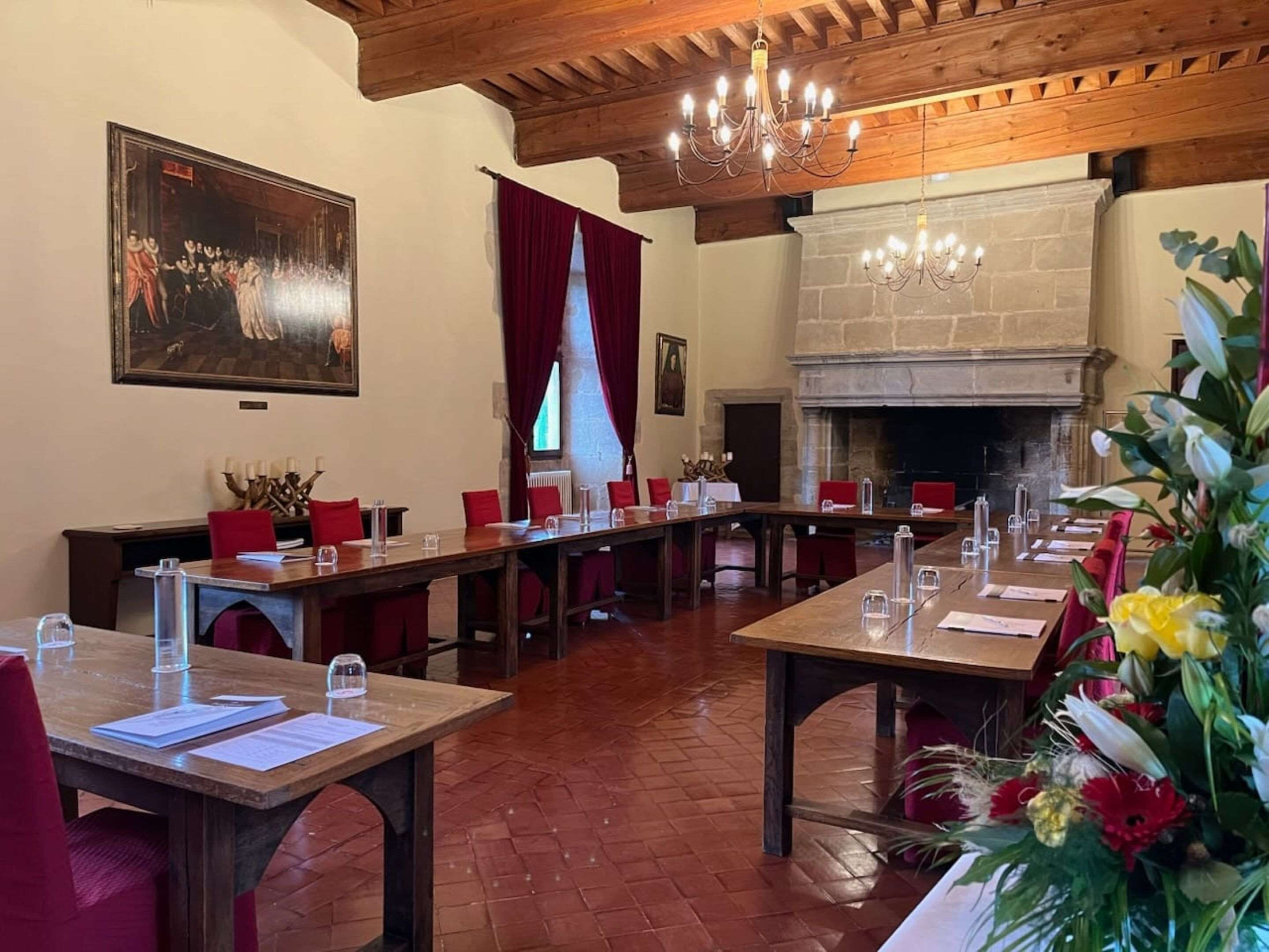 A conference room with long tables, red chairs, and a fireplace.