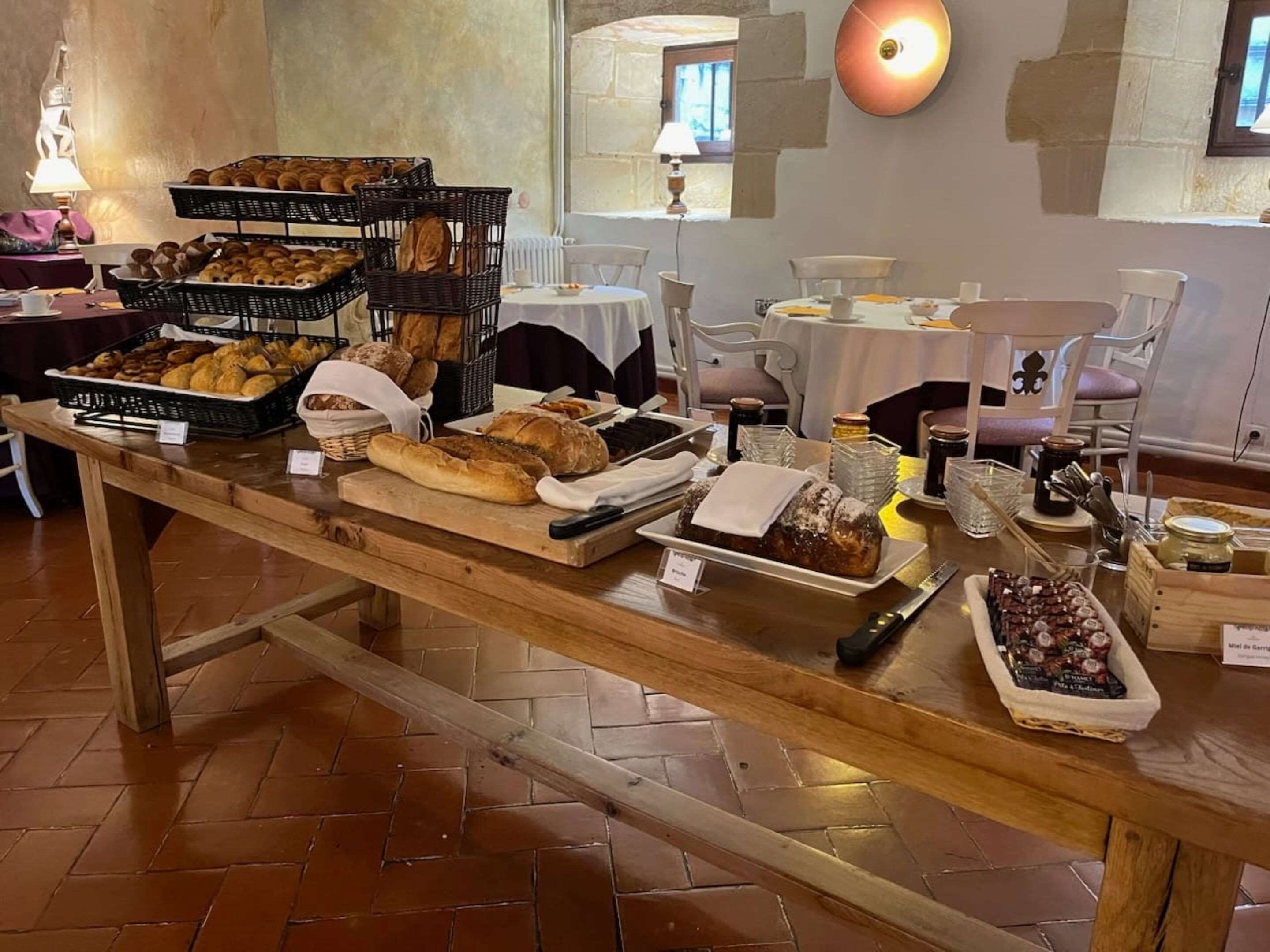 A breakfast buffet with various breads, pastries, and jams.
