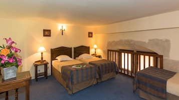 A hotel room with two beds, a desk, a chair, and a vase of flowers.