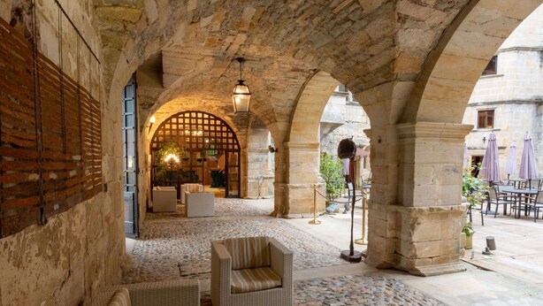 Un patio interior con arcos de piedra, una zona de estar y vistas a la calle.