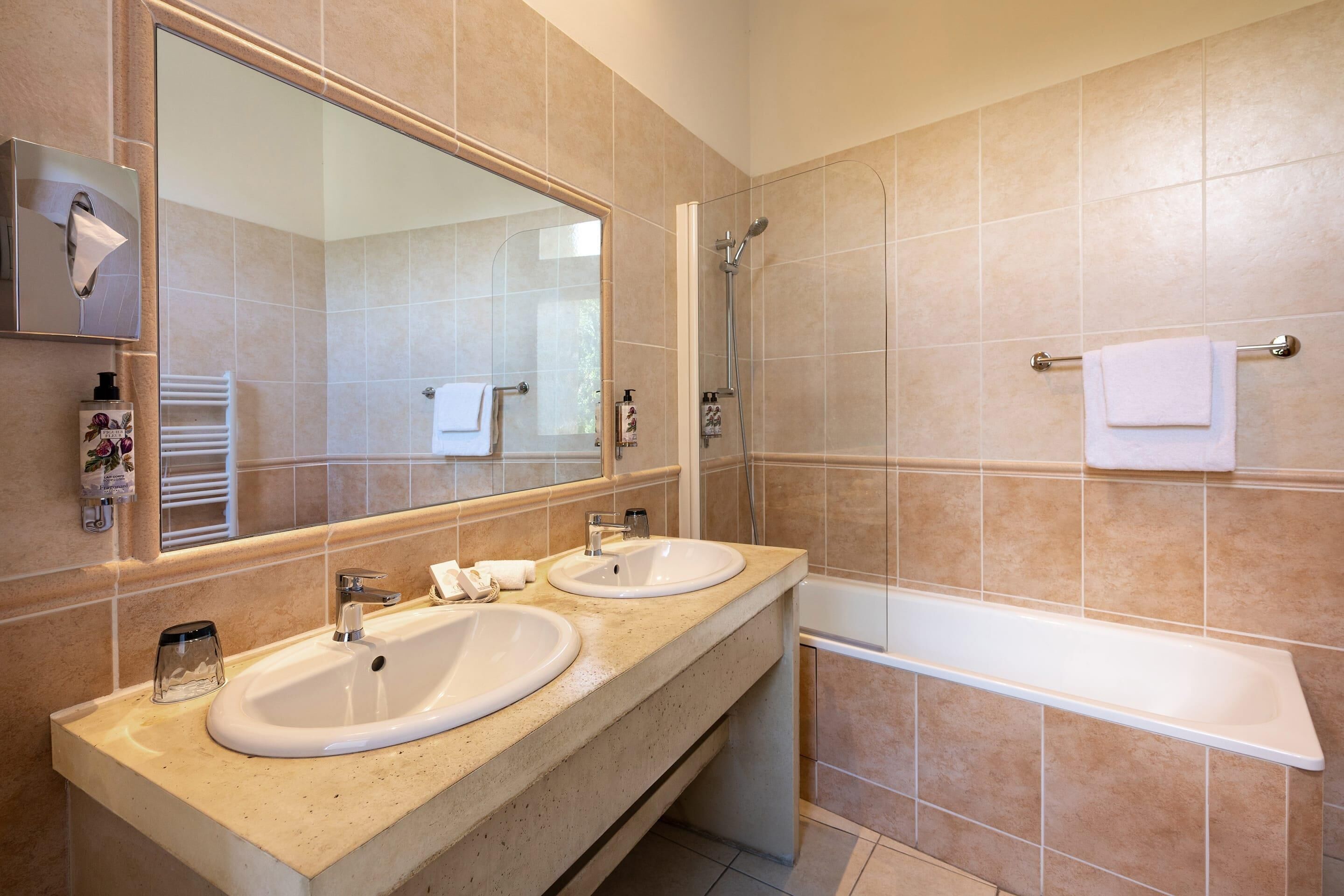 A bathroom with two sinks, a large mirror, a shower, and a bathtub.