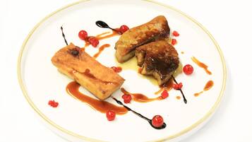 A plate with three pieces of food, garnished with red berries and a sauce.