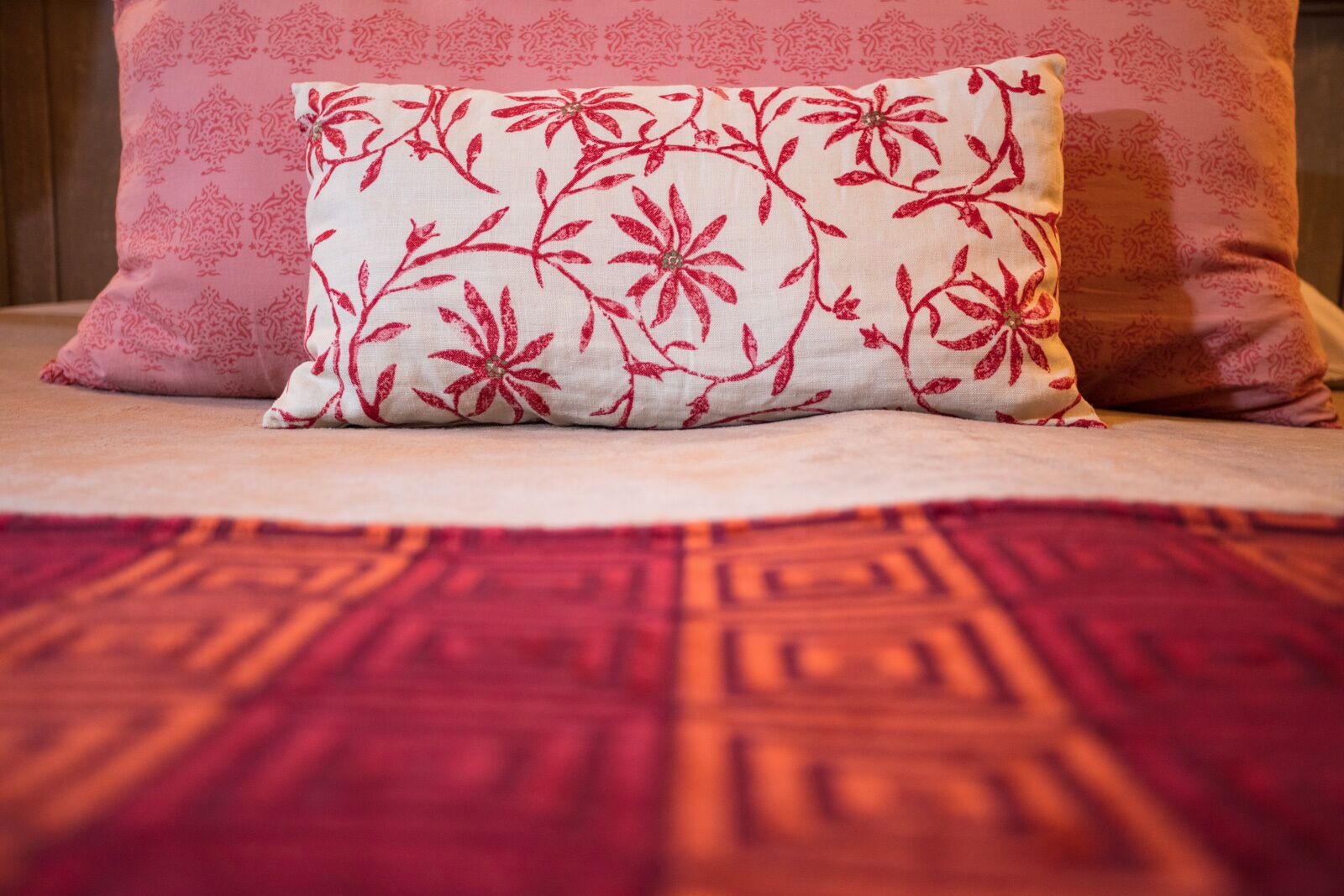 A bed with a patterned pillow and a geometric patterned bedspread.