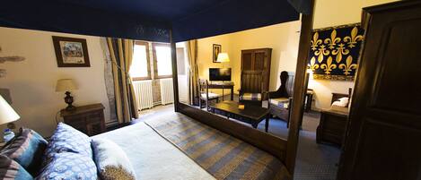 A hotel room with a large bed, a desk, a chair, a television, and a mirror.