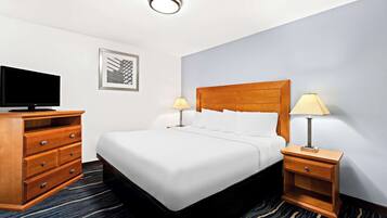 A hotel room with a bed, a TV, a wooden dresser, and two bedside lamps.