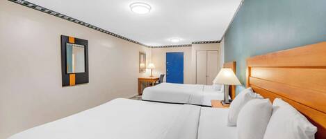 A hotel room with two beds, a desk, a chair, a lamp, and a mirror.