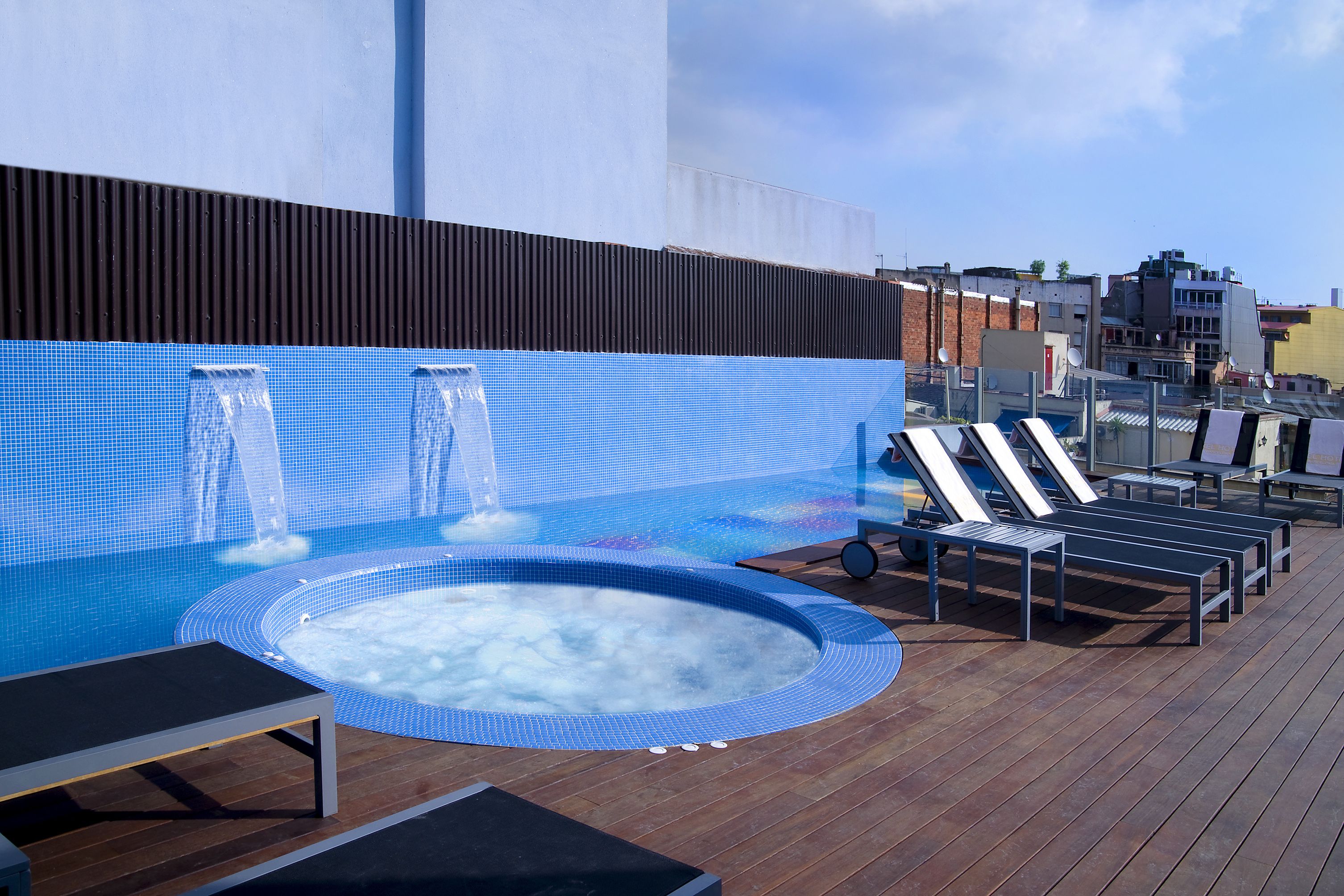 Een dakzwembad met een jacuzzi, ligbedden en een houten terras.