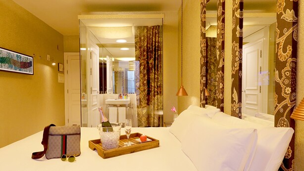 A hotel room with a bed, a tray with a bottle and glasses, and a suitcase. - Axel Hotel Barcelona - Adults Only (Barcelona)