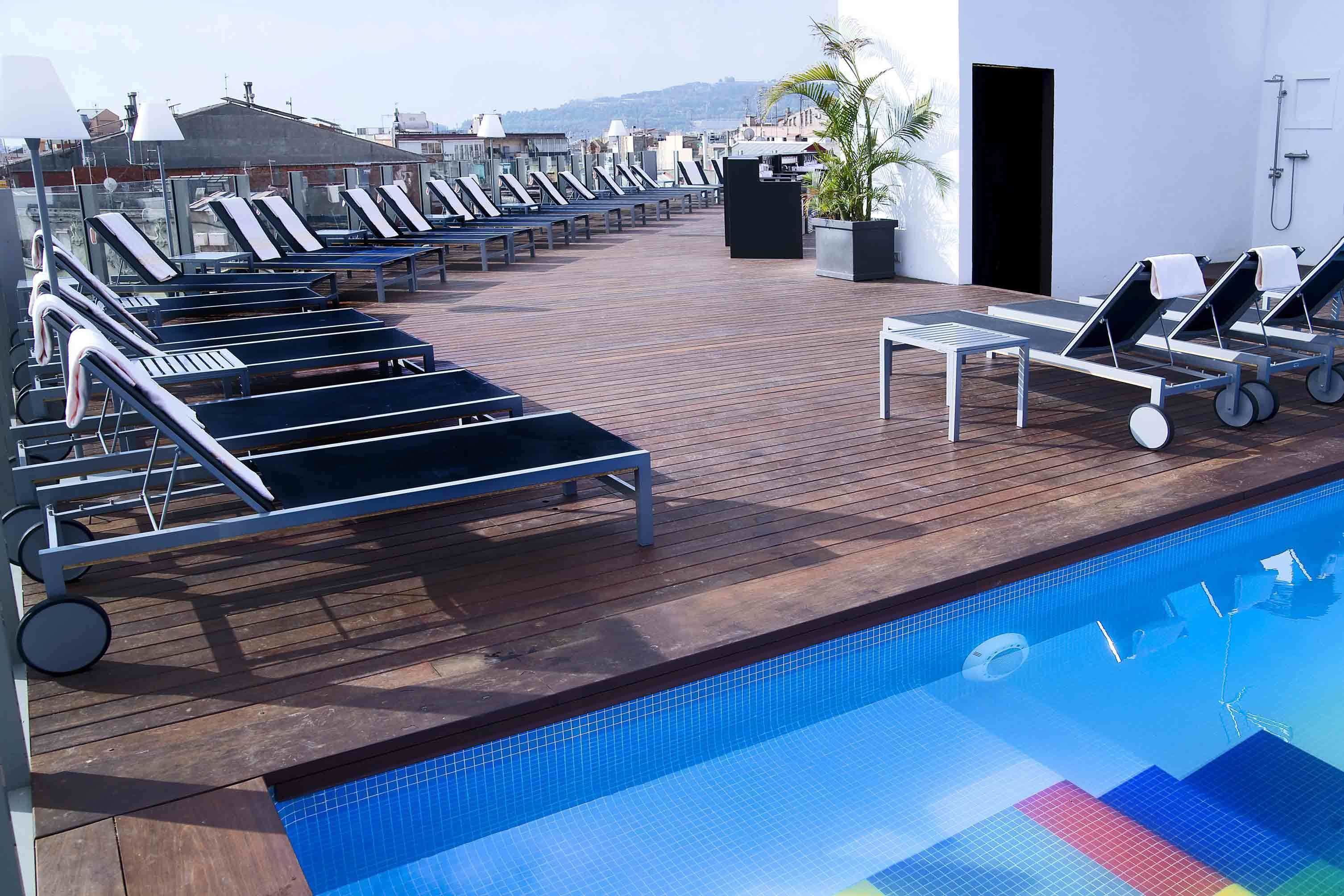 A rooftop pool area with sun loungers and a small table.