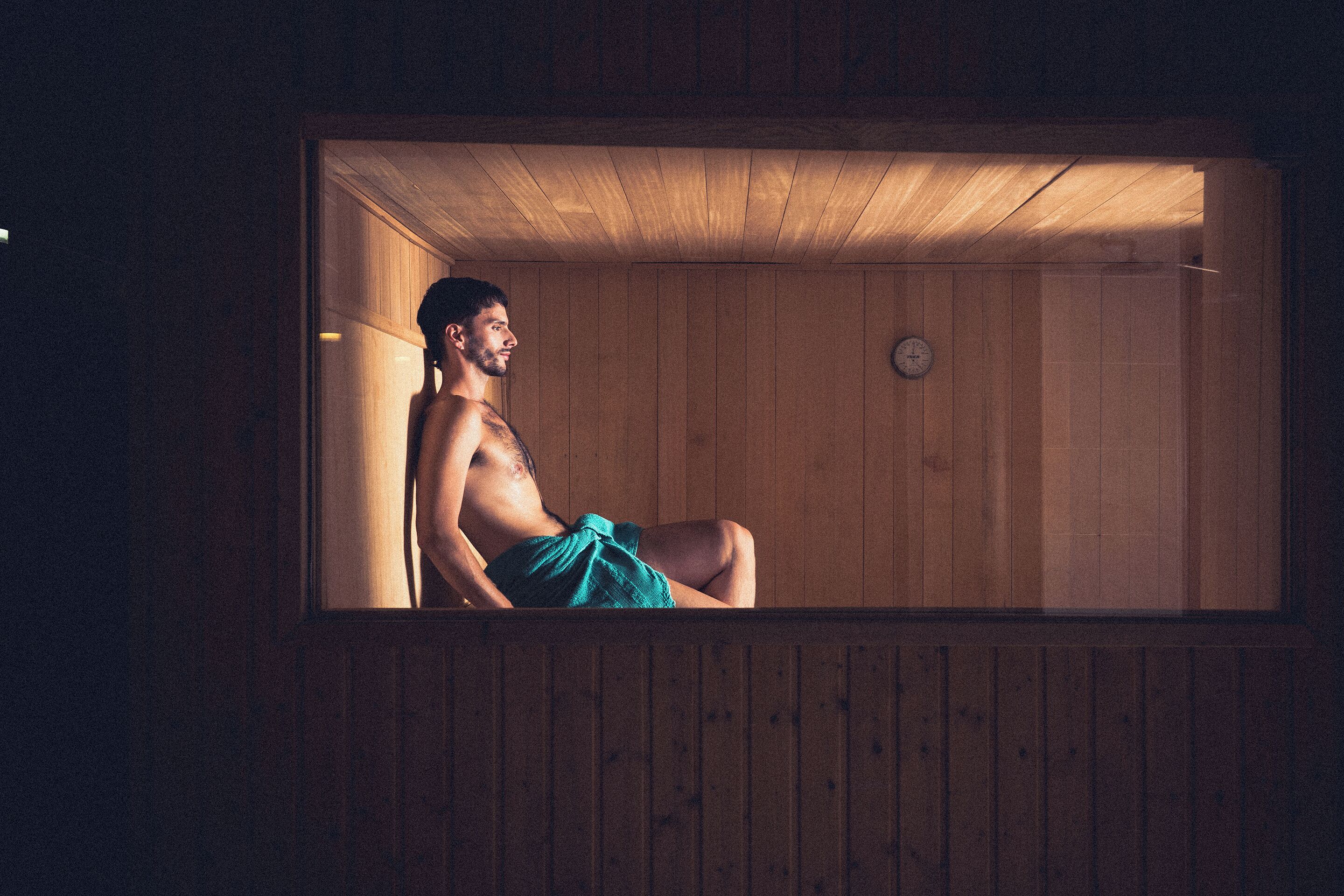 Una sala de sauna con paredes de madera y un reloj visible.