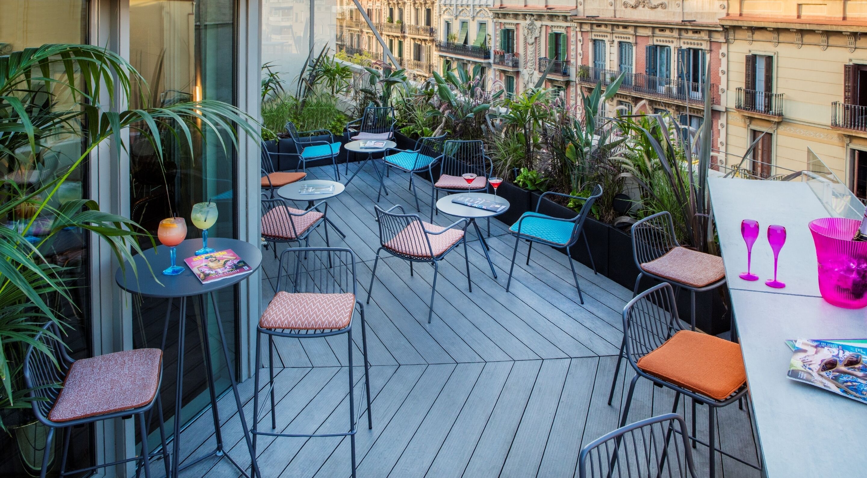 Une terrasse sur le toit, aménagée avec des espaces de détente en plein air, des plantes et offrant une vue sur le paysage urbain.
