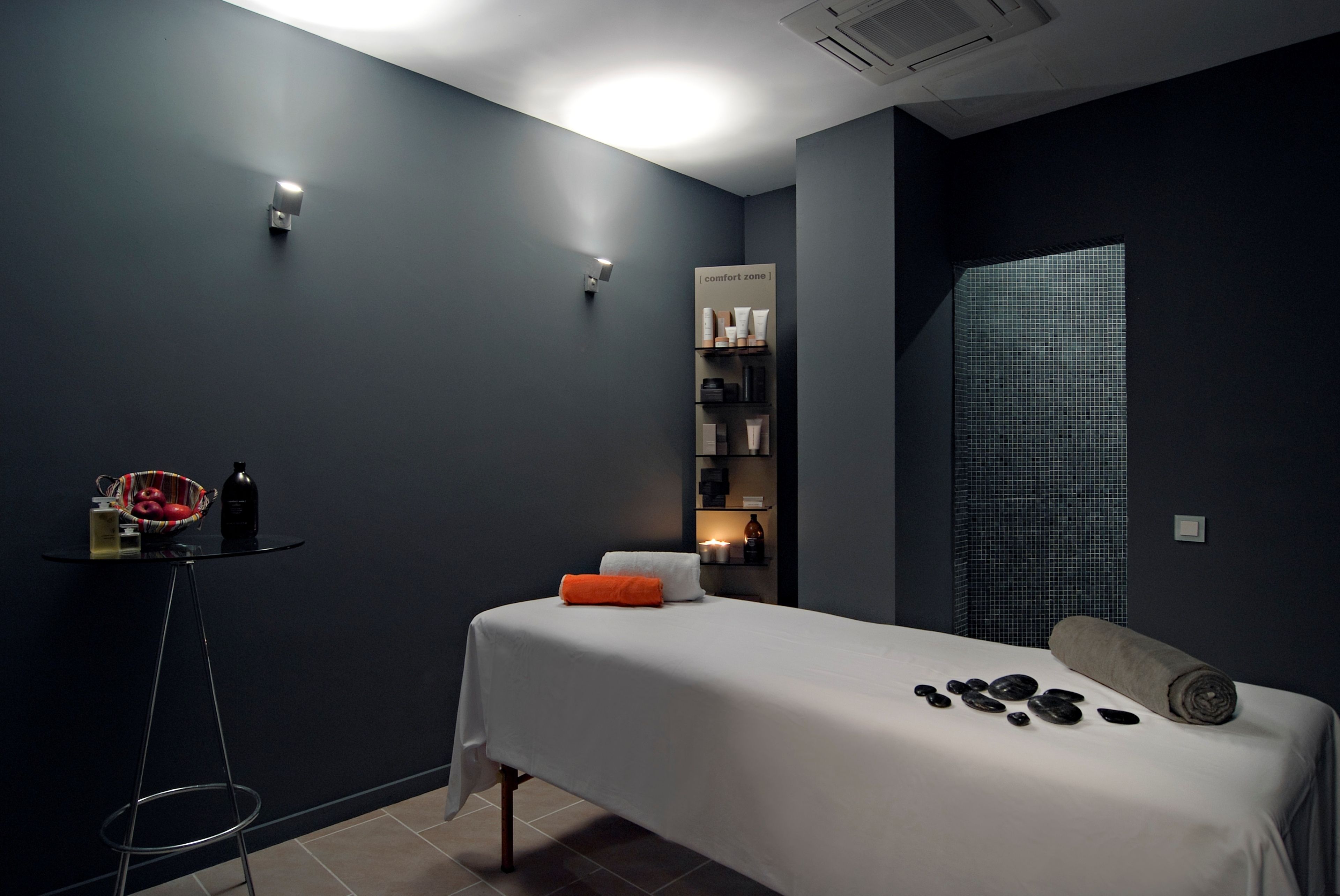 Un dormitorio moderno con una cama, una mesita de noche con una cesta y una estantería con artículos de aseo.