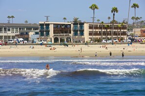 A beach hotel with multiple floors, a parking area, and palm trees. - Ocean Beach Hotel (San Diego)