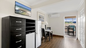 A compact room with a kitchenette, a dining area, and a view of the outdoors. - Ocean Beach Hotel (San Diego)