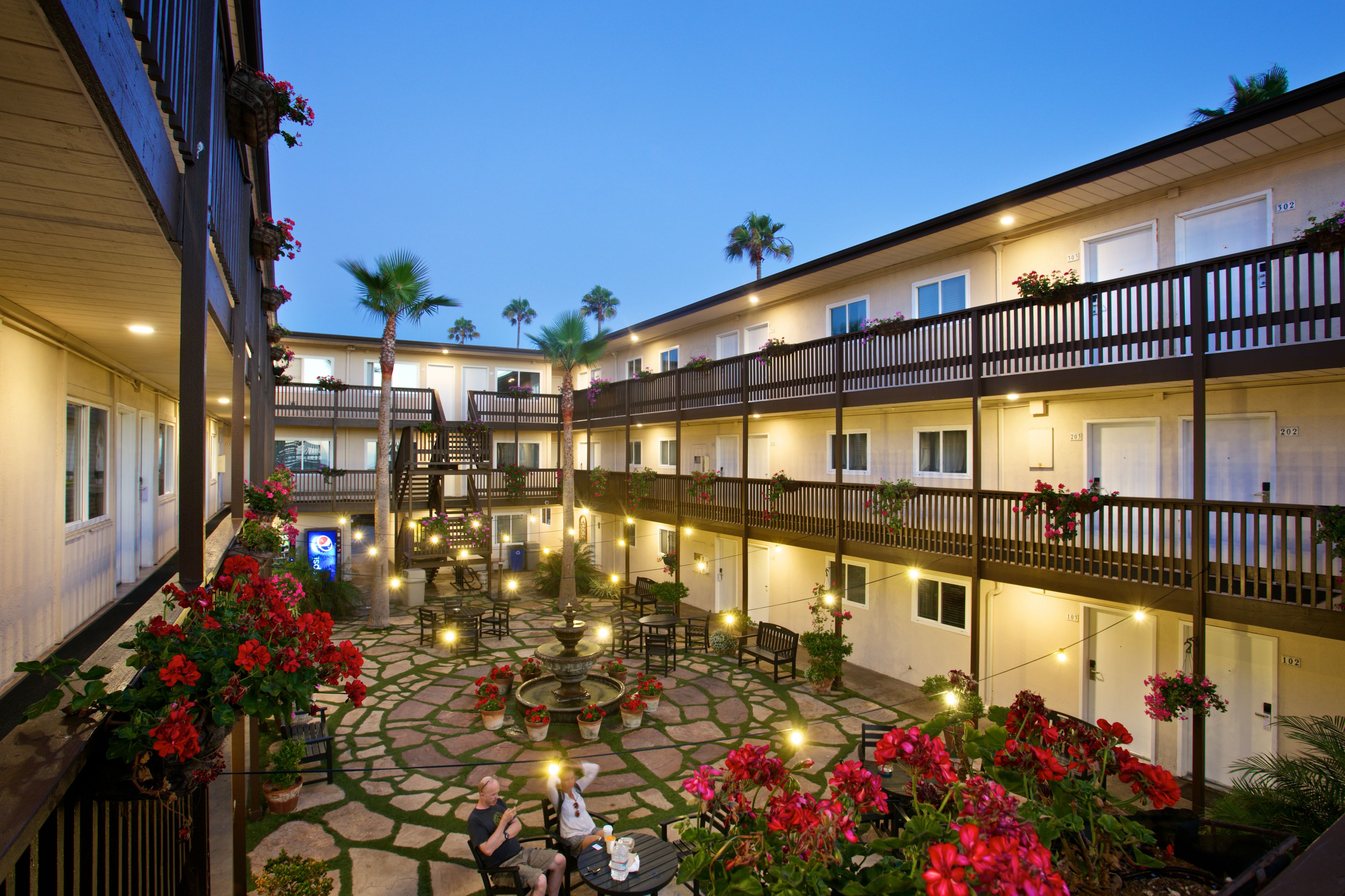 A courtyard with a fountain, outdoor seating, and potted plants.