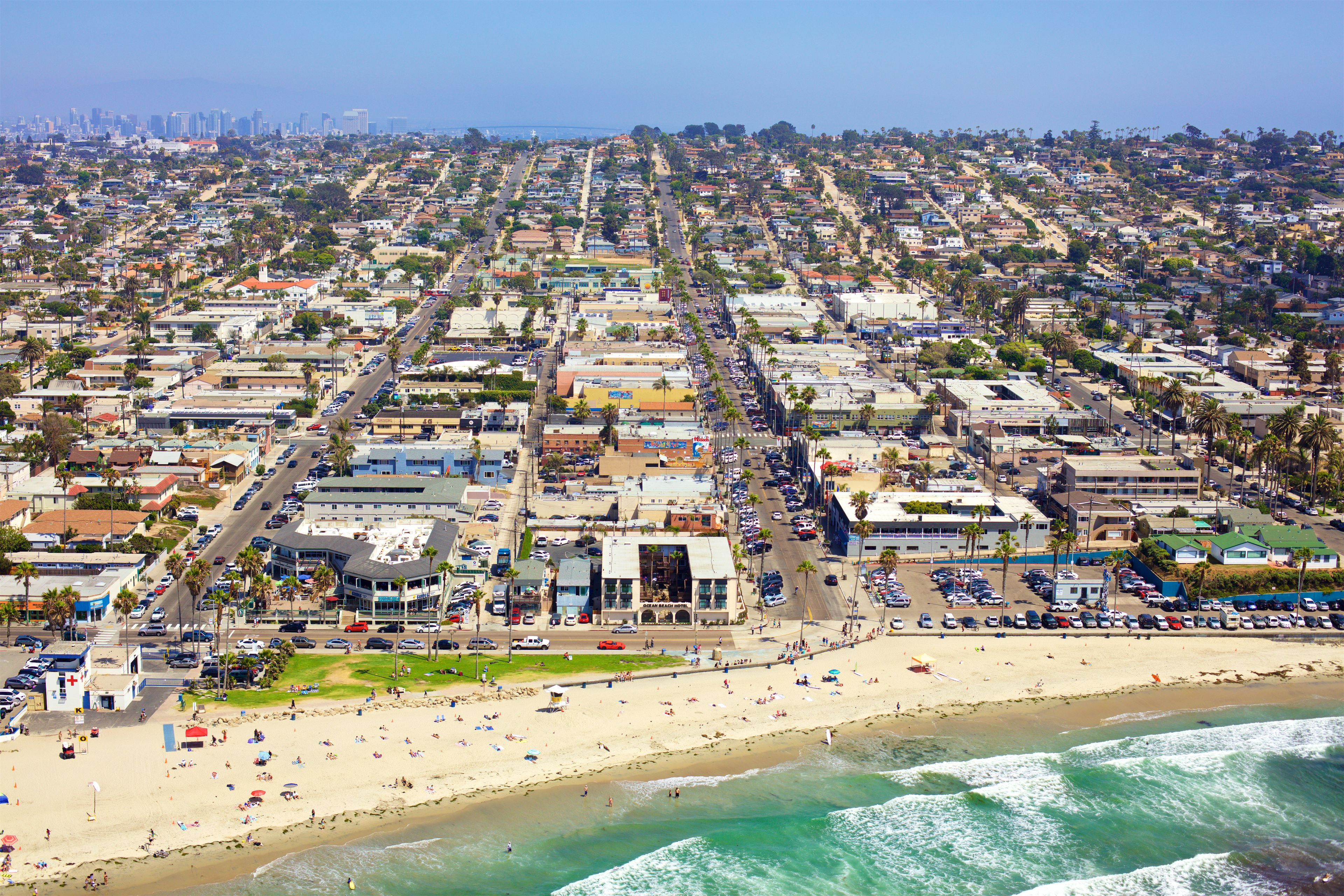 A coastal cityscape with a beach, buildings, and a clear sky.