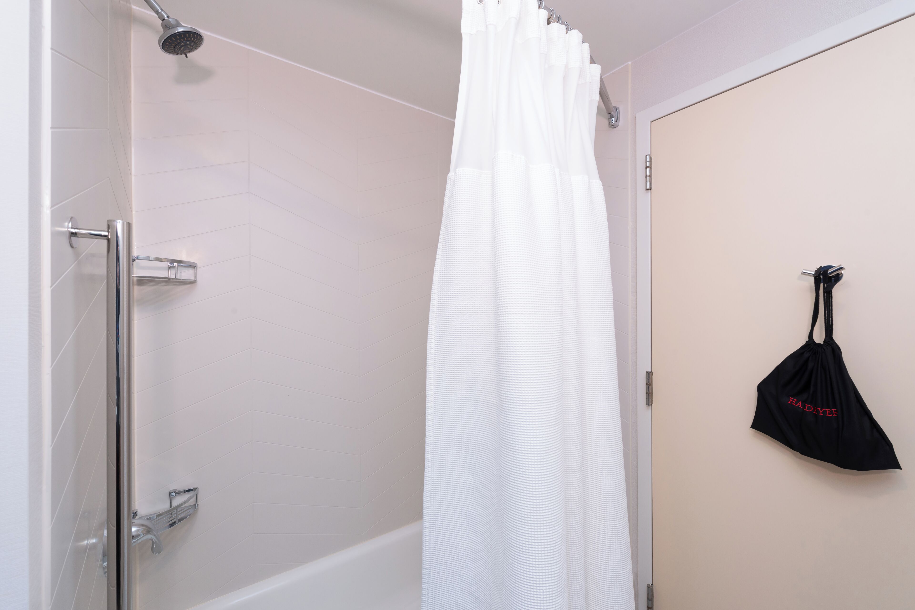 A bathroom with a shower, a toilet, and a towel rack with a towel.
