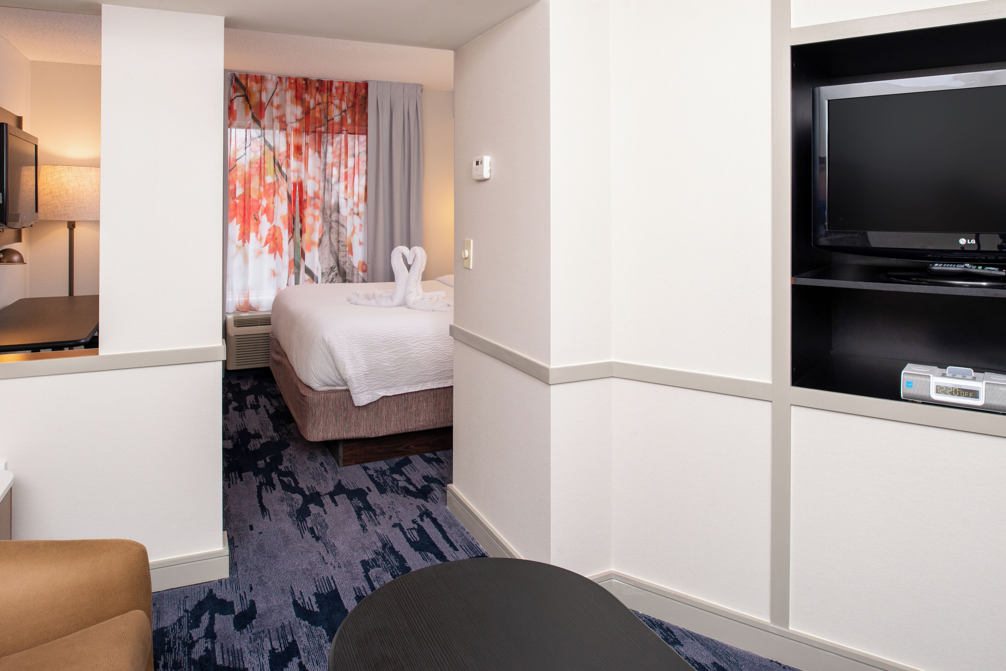 Una habitación de hotel con una cama, televisor, escritorio y una silla.