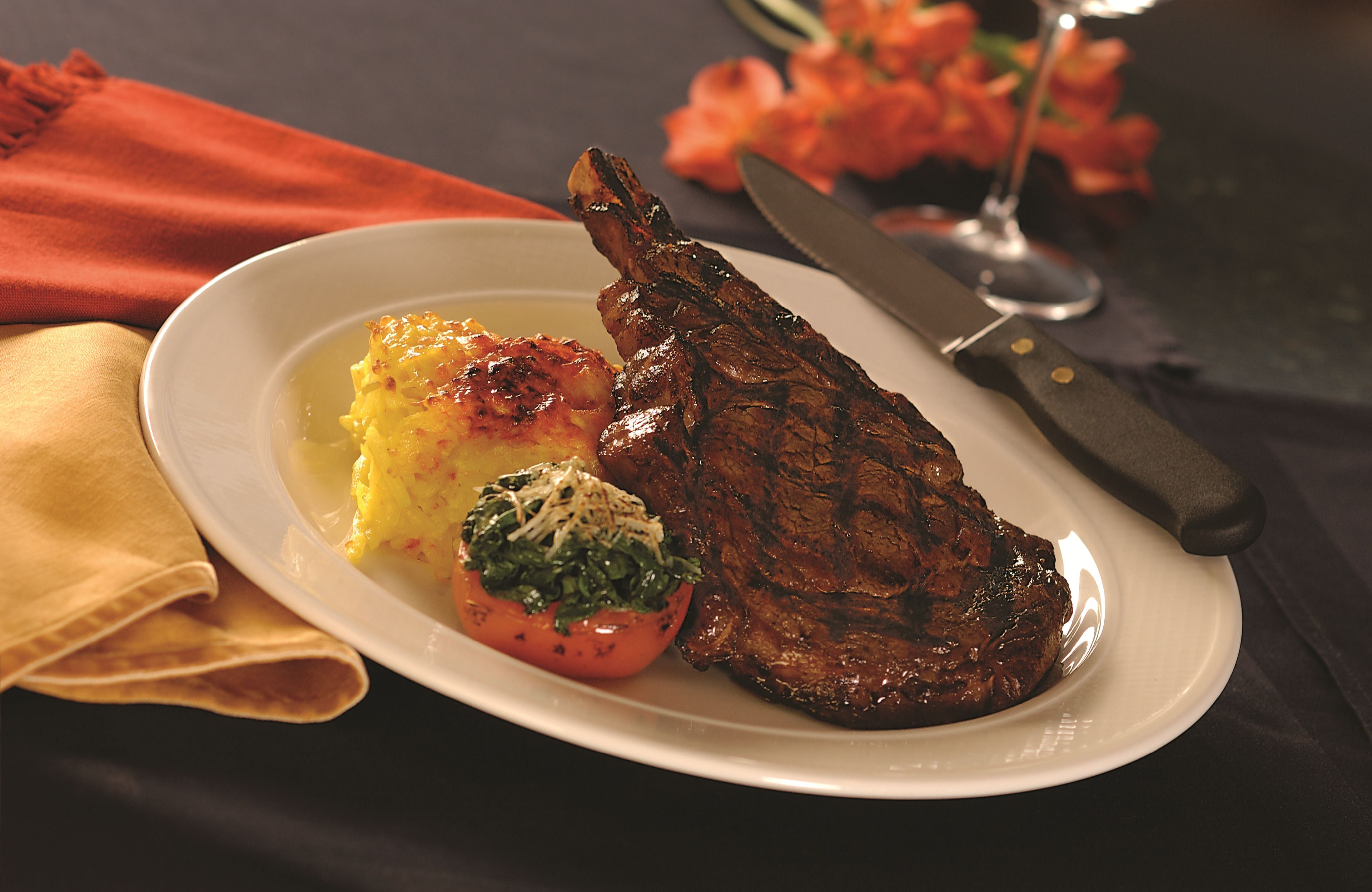 A plate with a grilled steak, mashed potatoes, and a grilled tomato.