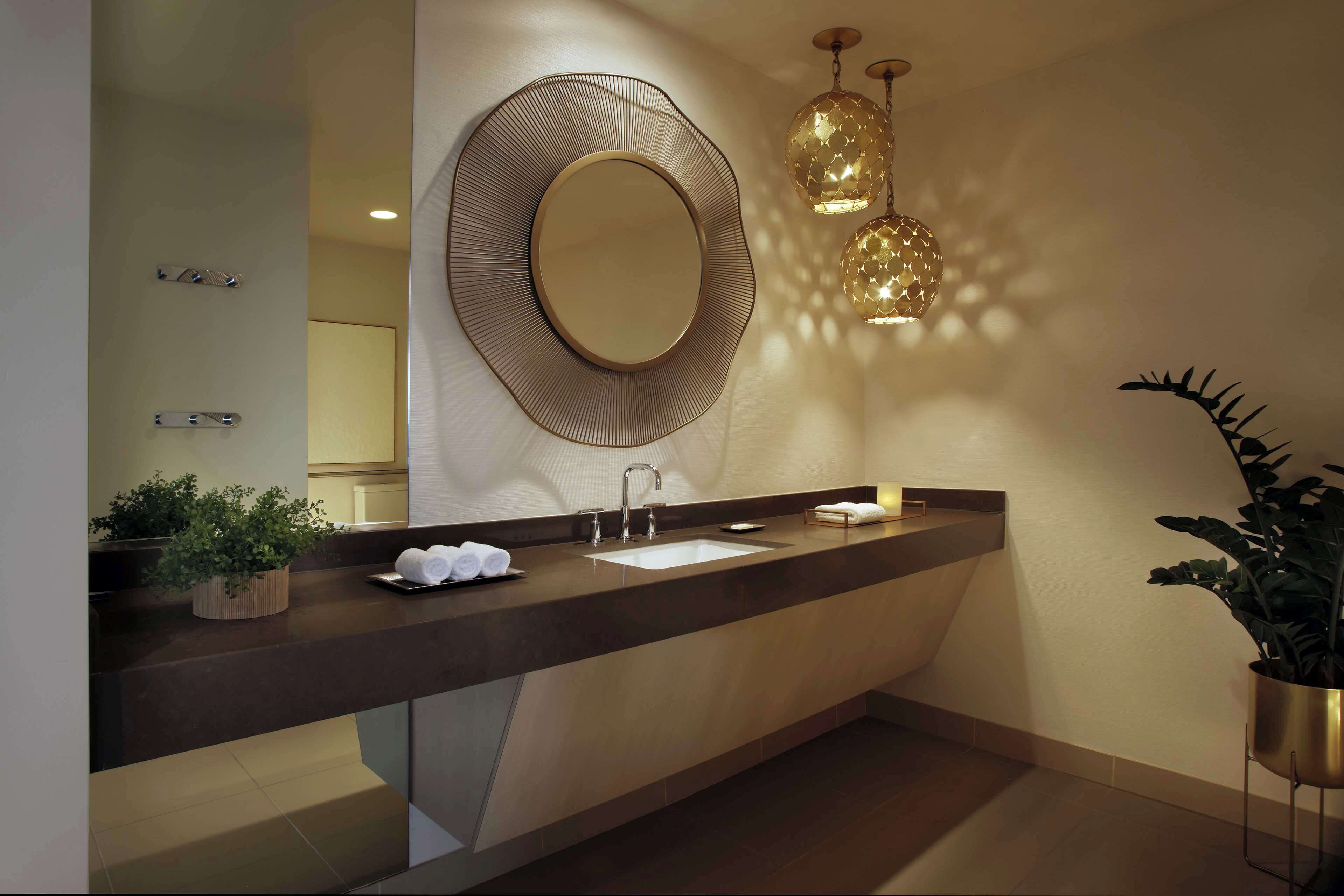 A modern bathroom with a large mirror, a sink, and two pendant lights.
