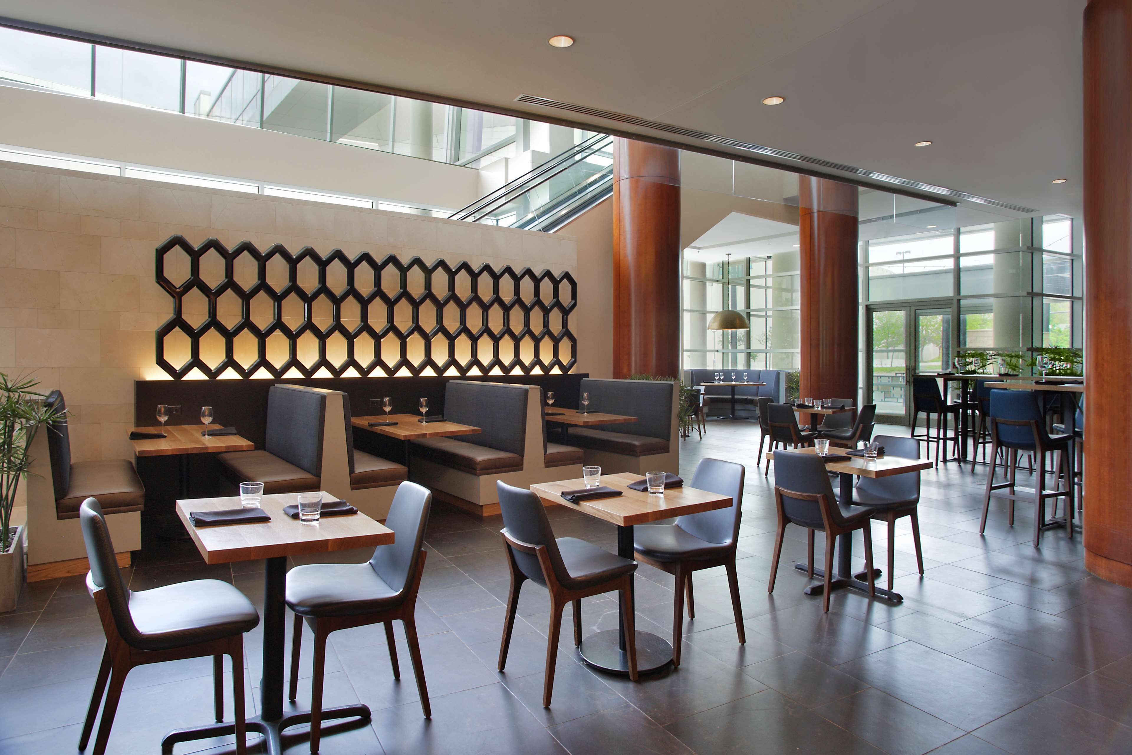 A modern restaurant with high ceilings, large windows, and a variety of seating options including booths and tables.