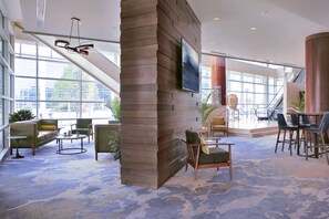 A spacious lobby with a high ceiling, large windows, and a modern interior design.