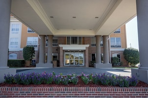 A building entrance with a brick facade, large glass doors, and a covered walkway.