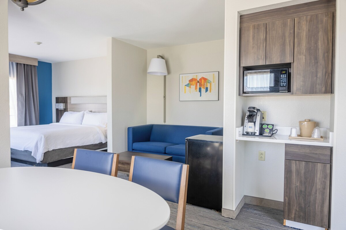 Une chambre d’hôtel comprenant un lit, un canapé bleu, une table à manger et une kitchenette équipée d’un four à micro-ondes.