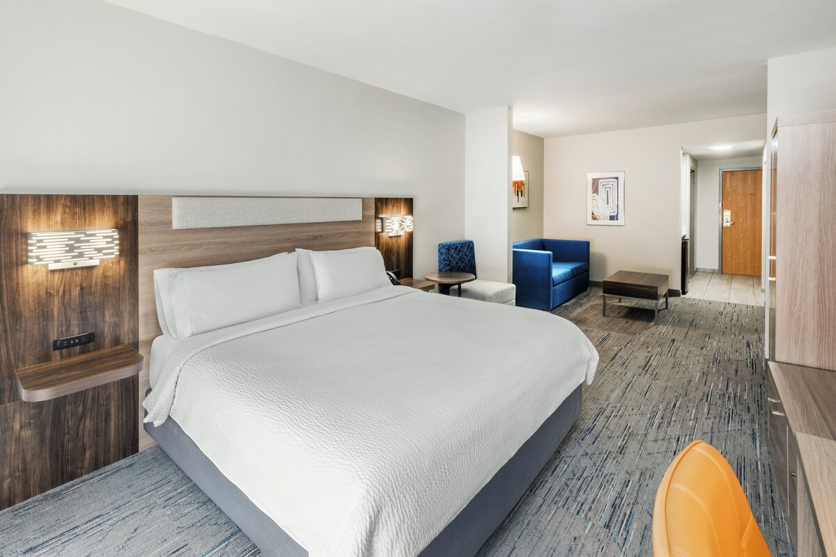 Une chambre d’hôtel avec un grand lit, des tables de chevet, un bureau, une chaise et une armoire.