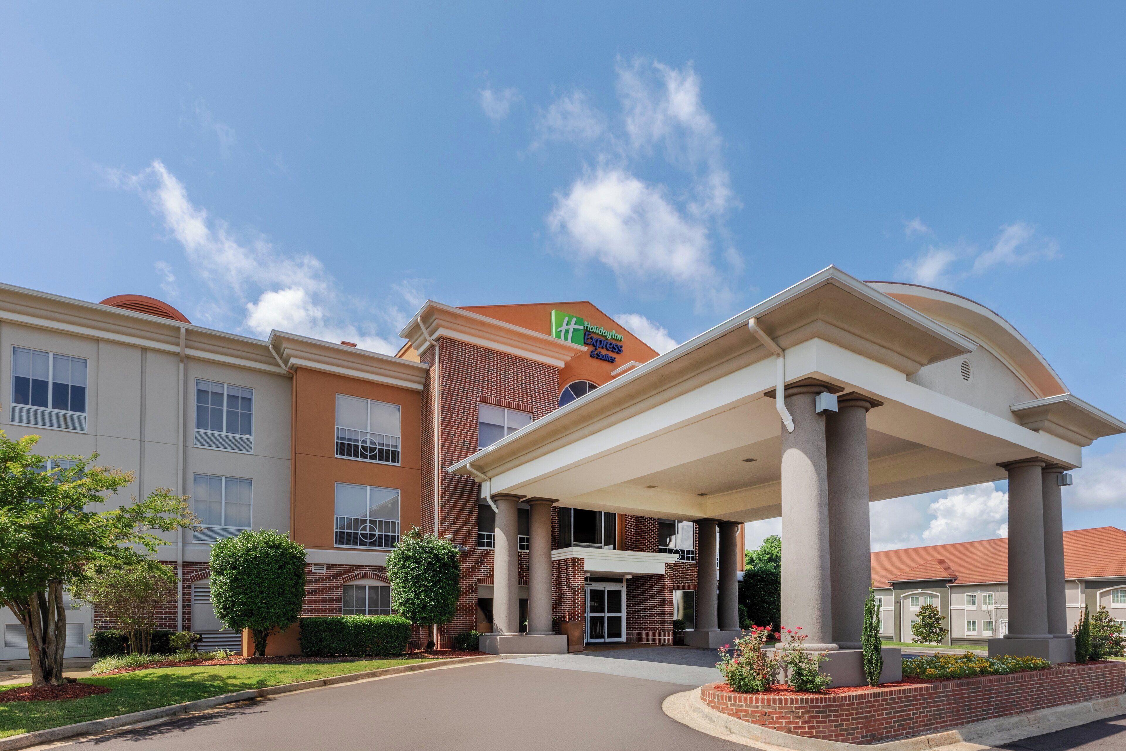 A Holiday Inn Express hotel with a covered entrance, brick facade, and a clear blue sky.