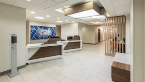 A reception area with two counters, a blue geometric wall, and a modern ceiling design.
