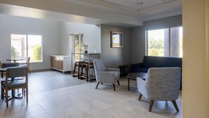 Une pièce spacieuse comprenant un coin repas, un coin salon avec un canapé bleu et une kitchenette.