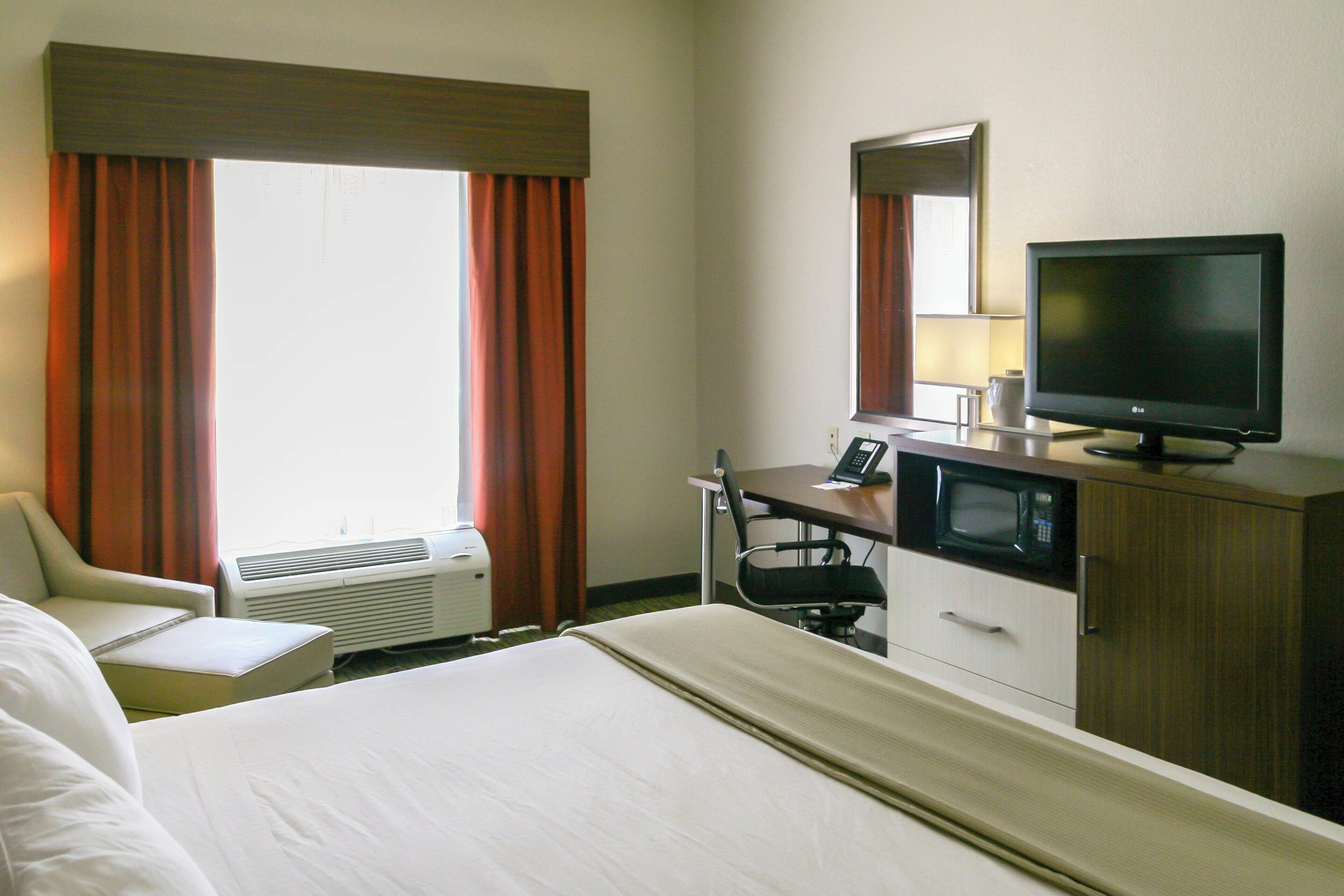 Une chambre d’hôtel équipée d’un lit, d’un bureau avec un ordinateur et un téléphone, d’une chaise et d’un téléviseur.