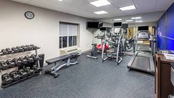 A gym with treadmills, elliptical machines, and dumbbells.