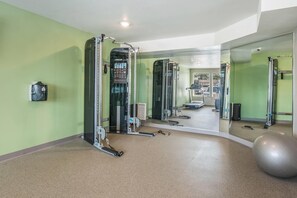 A gym with exercise equipment, a mirrored wall, and a large exercise ball. - WoodSpring Suites Chicago Midway (Burbank)