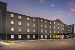 A multi-story hotel with a flat roof, large windows, and a parking lot in front. - WoodSpring Suites Chicago Midway (Burbank)