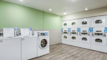 A laundry facility with multiple washing machines and dryers, a scale, and a digital display.