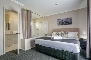Habitación de hotel con una cama grande, un baño con bañera, ducha e inodoro.