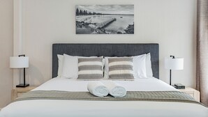 A hotel room with a large bed, two bedside lamps, a headboard, and a framed picture on the wall. - Mandala Ace Albany Hotel (Centennial Park)